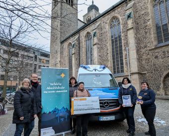 Menschen mit einem Spendenscheck vor einer Kirche