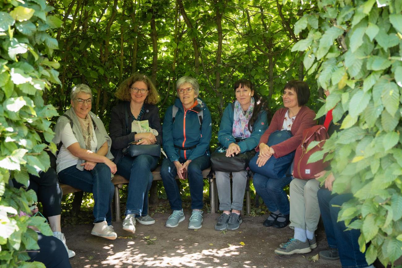 Frauen sitzen in einer grünen Hecke