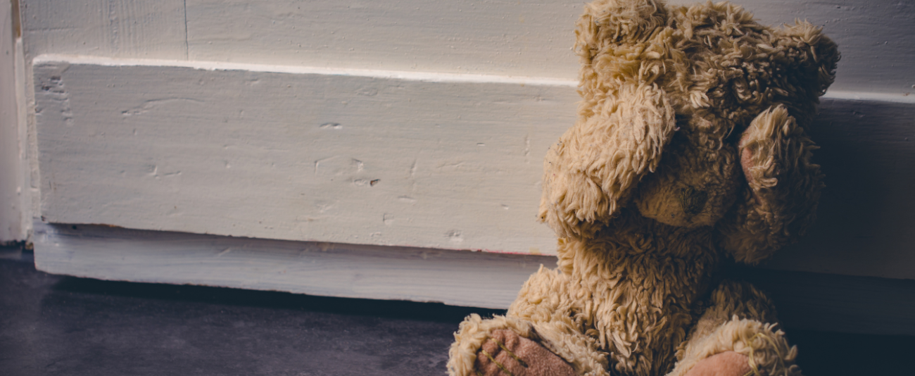 EIn Teddybaär sitzt auf dem Boden und hält sich die Augen zu