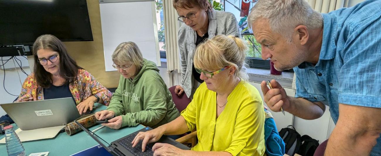 Menschen stehen und sitzen vor Laptops