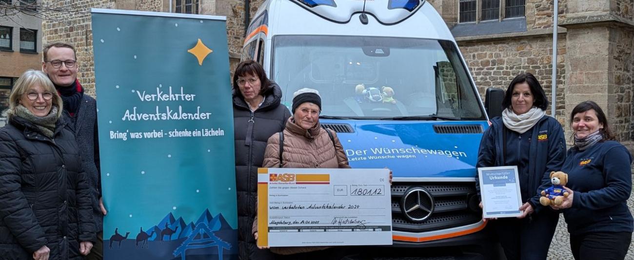 Menschen halten einen Scheck vor einem Auto